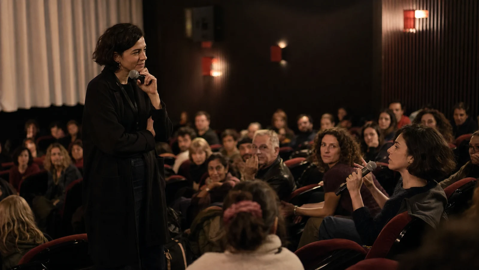 Thoughtful moderator listening to an audience question with a handheld microphone