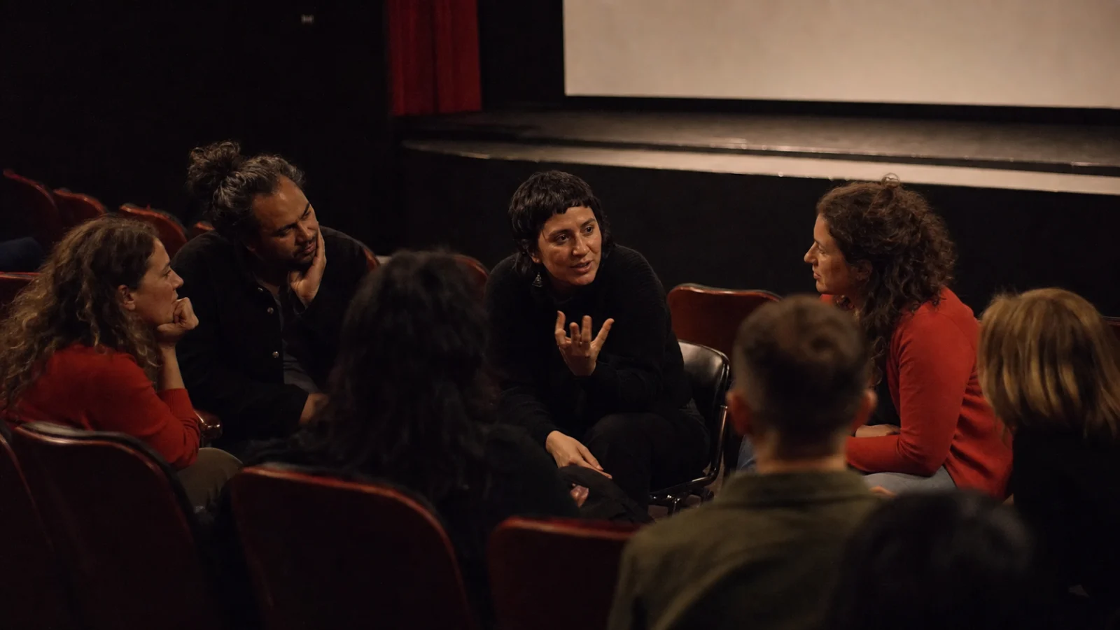Audience members exchanging ideas in an intimate cinema after a screening